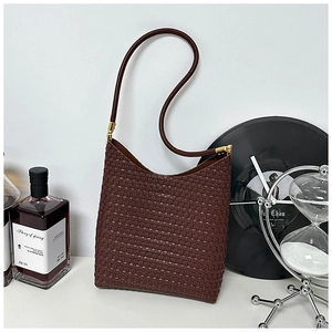 Detail of soft woven texture on dark brown large tote bag with elegant gold metal accents