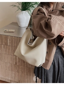 Close-up of a cream white lychee leather tote bag worn by a model in a natural setting