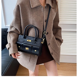 Détail d'un sac à main noir à texture tissée avec boucles à verrouillage doré