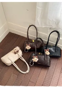 Detail view of four pleated underarm bags in white, brown, coffee and black with charms
