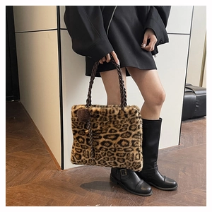 Close-up of leopard faux fur tote with woven handle and dark pompom charm detail