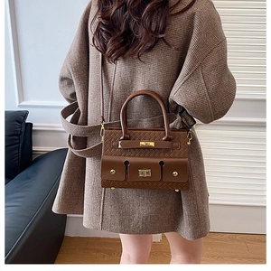Vue détaillée de la texture tressée du sac marron avec boucle en métal doré élégante