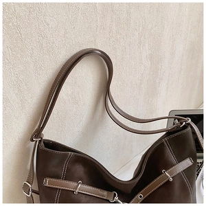 Detail of dark brown tote bag with contrast stitching and silver metal buckles