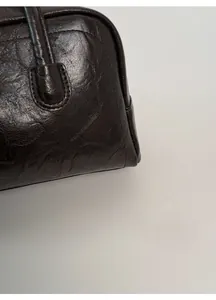 Macro detail of retro dark brown bag showing the wrinkled oil wax leather texture and stitching