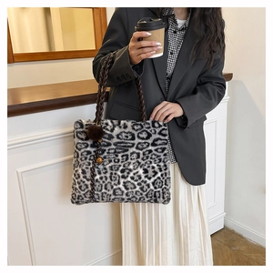 Detail of plush leopard print tote bag with thick woven handles and pompom charm