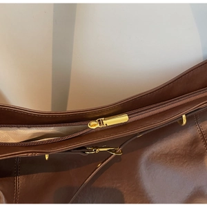 Detail of brown leather bag showing gold zipper, textured lining and fine stitching
