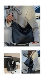 Detail of a large black lychee textured leather bucket tote with an adjustable strap