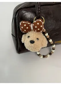 Detail of plush dog charm with bead chain on brown leather shoulder bag