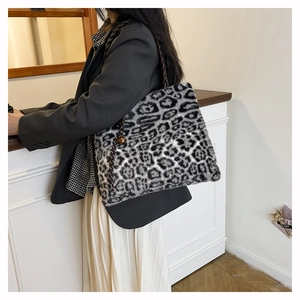 Detail of plush leopard print tote bag with brown woven handle and bell charm