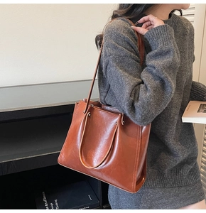 Brown oil wax leather tote bag shown on a model with a dark grey knit dress