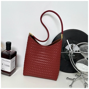 Detailed view of dark red woven leather tote bag with elegant gold metal ring accents