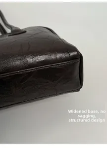 Detail view showing the widened bottom and structured base of the glossy leather bag