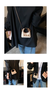 Detail van beige mini-crossbodytas met bruine bloemapplicaties en ronde handgreep