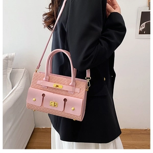 Détail du sac à main rose à texture tissée avec boucle dorée porté par un mannequin