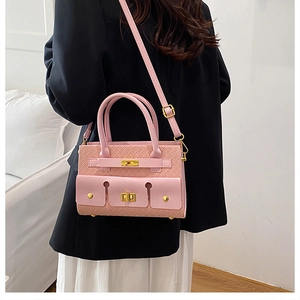 Détail d'un sac à main rose à texture tissée avec fermoir doré et bandoulière réglable