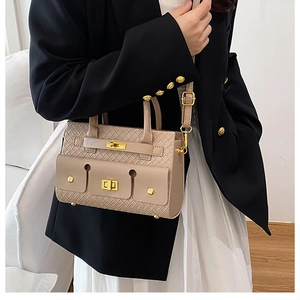 Détail du sac à bandoulière beige à texture tressée avec fermoir rotatif en métal doré