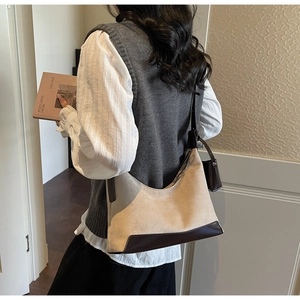 Detail shot of a minimalist retro crossbody bag showing the beige suede and brown leather texture