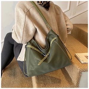 Detail of dark green leather tote bag with white contrast stitching and buckle straps