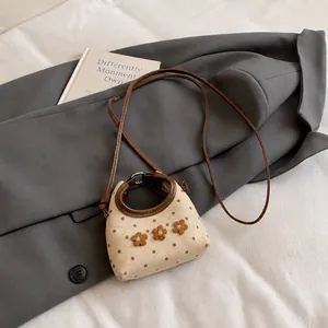 Detail van mini canvas tas met bruine stippen en 3D-bloemaccenten op een beige stof