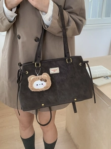 Brown vintage faux leather tote bag with plush charm and side drawstring detail