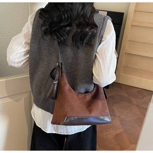 Detail of a dark brown suede Hobo bag with adjustable strap and a mini charm pouch