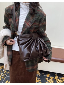 Close-up of coffee brown tote bag with pleated texture and adjustable strap in autumn setting