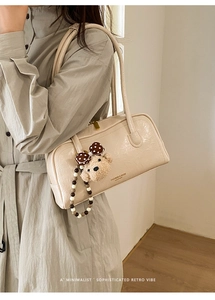 Detail of cream white leather Boston bag with a bear charm and pearl bead strap