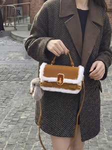Dettaglio borsa in camoscio marrone con bordo in finta pelliccia e chiusura dorata