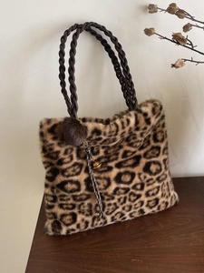 Faux fur leopard print tote bag with plush ball charm and brown woven handles