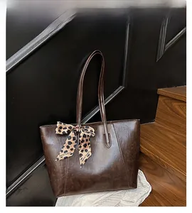 Detail of a brown tote bag with leopard print scarf on a wooden step background
