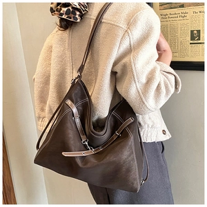 Detail of brown leather hobo bag featuring contrast stitching and side metal buckle