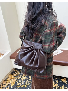 Close-up of a large dark brown pleated tote bag in an autumn outdoor setting