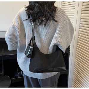 Detail of a black patchwork tote bag with mini pouch shown on a gray sweater