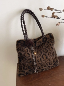 Large leopard print plush tote bag with woven handles and decorative pompom charms