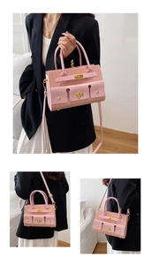 Détail du sac bandoulière rose avec texture tressée, fermoir doré et poignées fixes