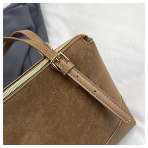 Detail of a brown shoulder bag featuring neat stitching and a gold-tone metal zipper closure