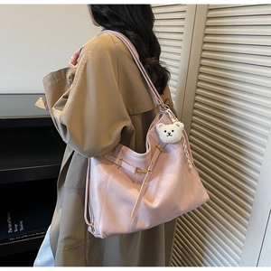 Pink vintage leather tote bag with gold hardware and plush bear charm shown on shoulder