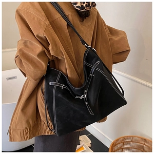 Detail of a large black matte leather tote with white contrast stitching and buckle straps