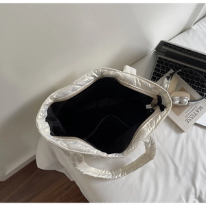 Macro view of white quilted tote bag interior showing spacious black liner and inner pocket