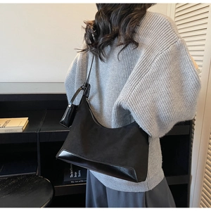 Detail of black crescent shoulder bag with matte leather finish and hanging coin purse