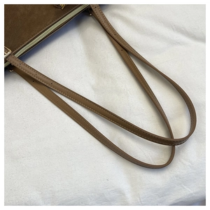 Detail of adjustable brown leather strap with fine stitching and gold-tone buckle