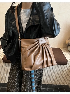 Detail of vertical pleated brown leather tote bag with elegant metallic logo label
