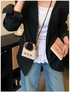 Detailopname van de mini canvas crossbodytas met bloemenborduursel bij een straatstijlmodel