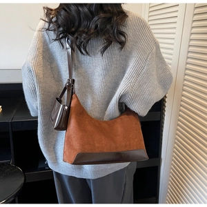 Brown suede half-moon underarm bag with matching mini pouch shown on a shoulder