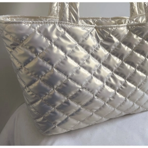 Close-up of metallic silver quilted tote bag showing shiny texture and diamond stitching