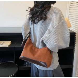 Detail of vintage brown suede tote bag with leather base worn over a grey knit sweater