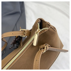 Close-up of brown leather tote bag showing gold zipper detail and fine texture
