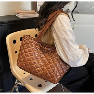 Detailed view of the quilted brown tote bag showing glossy waterproof fabric and stitching