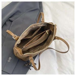 Detail view of large brown tote bag with multi-compartment interior and striped lining