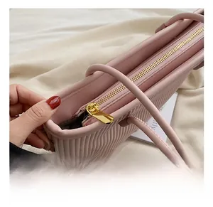 Detailed close-up of golden metal zipper and pink pleated texture on a tote bag